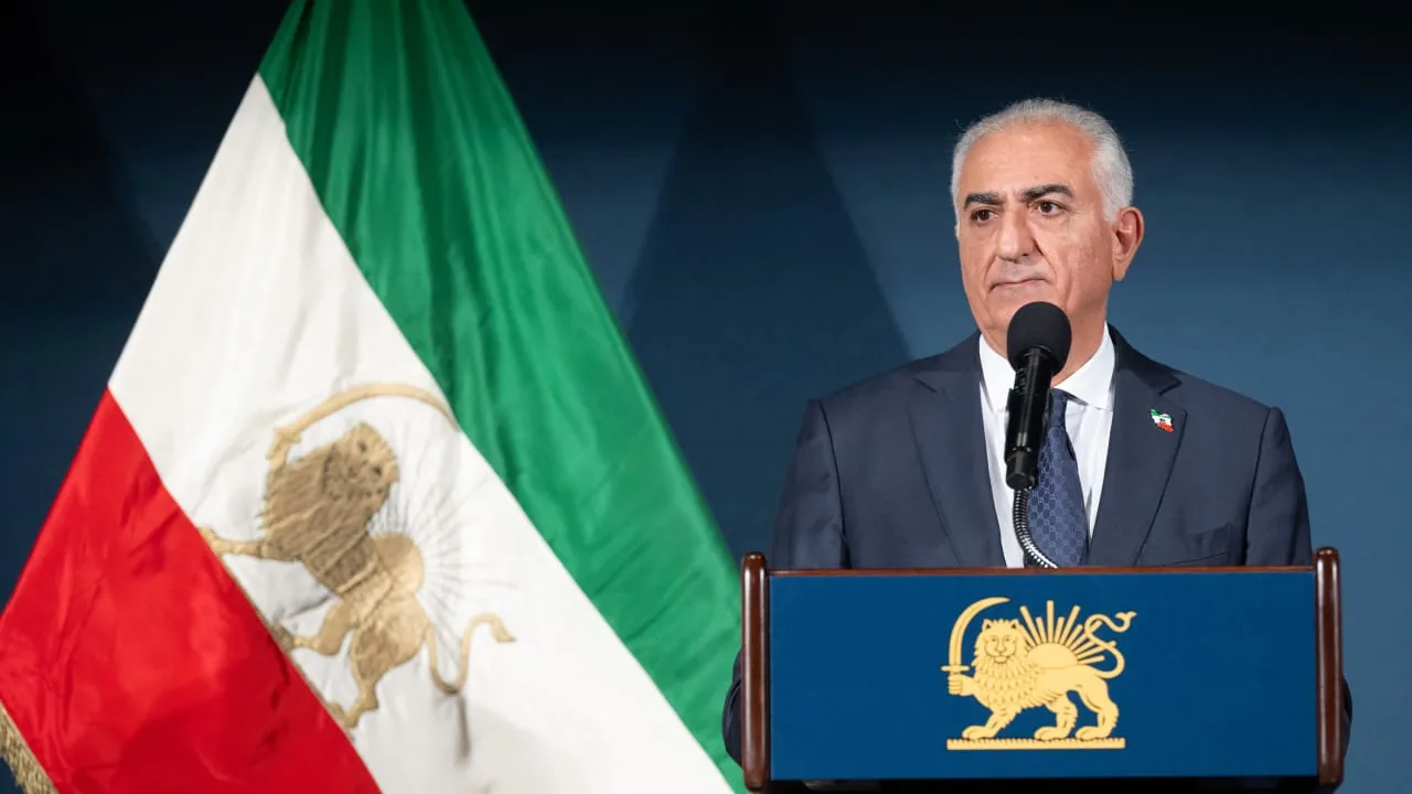 Reza Pahlavi speaking beside the Lion and Sun flag